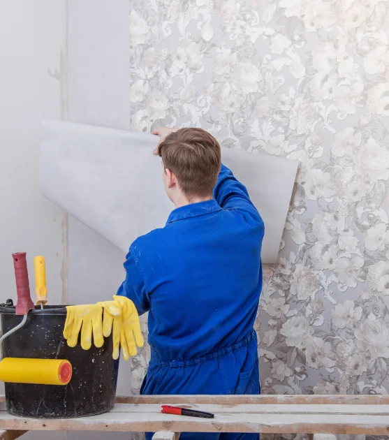 Wallpaper removal in progress, lifting the old wallcovering carefully by hand